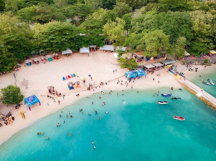 Aerial view of Mactan Newtown beach with swimmers, tents, and turquoise water.