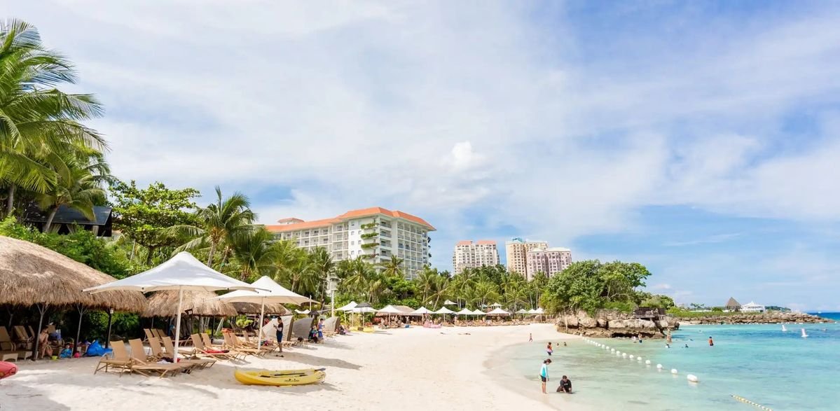 Shangri-La Mactan beach resort with white sand, lounge chairs, and clear blue water in Cebu.