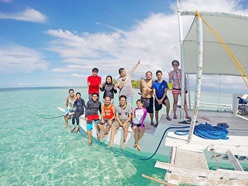 Group enjoying island hopping on a boat in clear waters of Mactan, Cebu.