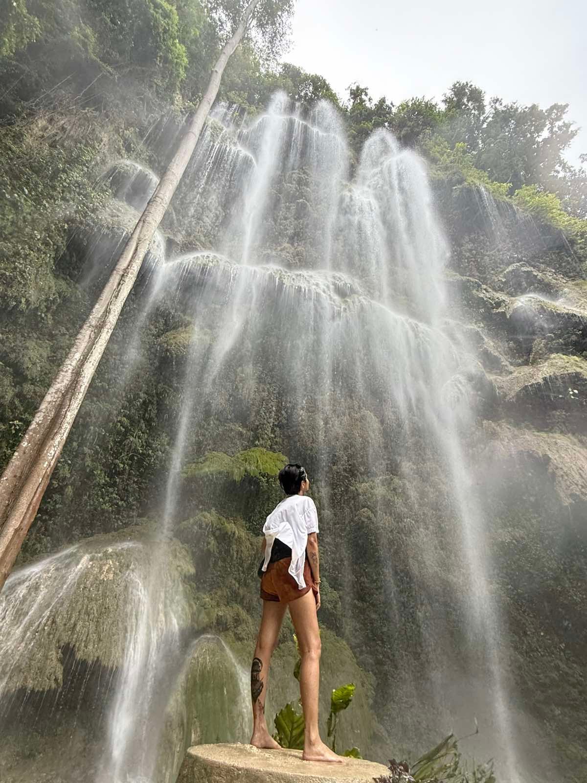 Home A traveler admiring the majestic, curtain-like Tumalog Falls in Oslob, a key destination in the all-inclusive South Cebu tours provided by Cebu Travels & Oslob Tours.